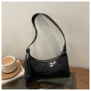 Detail view of a stylish black glossy underarm bag with a retro wrinkled patent leather texture