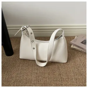 Elegant white glossy underarm shoulder bag displayed on a minimalist woven rug background.