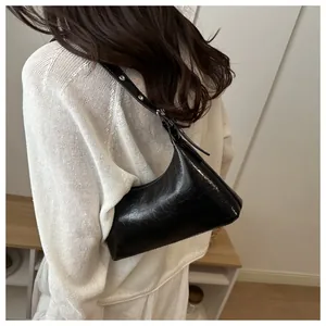 Back view of a woman wearing a white knit top with a chic black glossy underarm bag