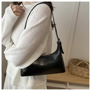 Close-up of black crackle texture underarm bag on shoulder with white knit sweater