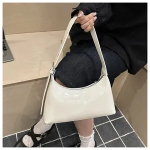 Cream white glossy underarm bag for women being held in a stylish street setting