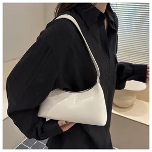 Side view detail of a glossy white minimalist underarm baguette bag on model's shoulder