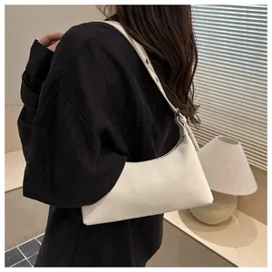 Detail view of stylish white textured underarm shoulder bag worn by a model in black