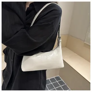 Detailed macro view of a stylish white glossy underarm bag worn over a black shirt