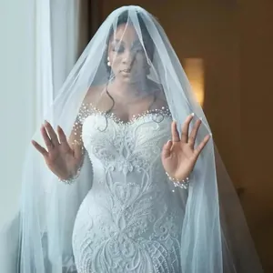 Elegant heavy lace mermaid wedding dress with pearl embellishments and long bridal veil.