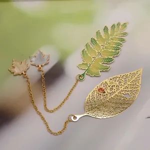 Detailed view of intricate brass leaf bookmarks with hollow veins and golden chains