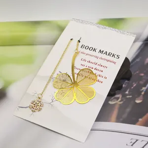 Detailed close-up of a golden four-leaf clover metal bookmark with a snowflake charm.