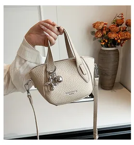 Elegant beige lychee texture handbag for women featuring a metallic balloon dog charm.
