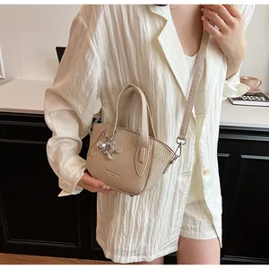 Detail view of a beige lychee pattern handbag featuring a cute balloon dog charm.