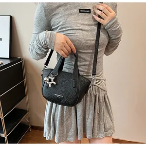 Detailed view of a black lychee-textured handbag with a cute balloon dog charm