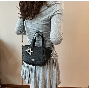 Detail of black lychee pattern crossbody bag with silver balloon dog charm