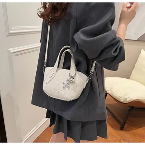 Lifestyle shot of a white lychee grain mini handbag with silver balloon dog charm