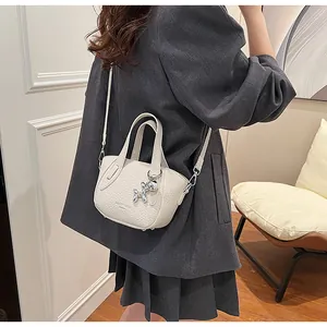 Woman carrying a stylish white lychee grain crossbody bag with a balloon dog charm