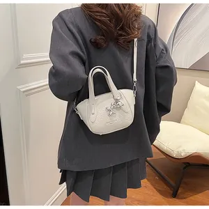 Detailed view of beige lychee pattern crossbody bag with cute balloon dog charm