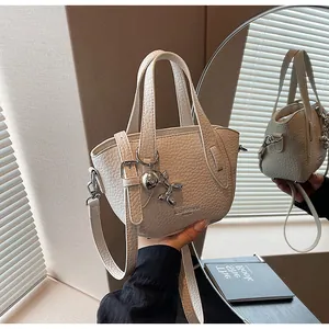 Close-up detail of white litchi grain handbag with stylish metallic balloon dog charm.