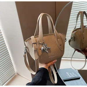 Close-up of beige litchi grain handbag with cute silver metallic bear charm