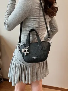 Stylish black lychee pattern handbag with silver balloon dog charm for women.