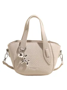 Elegant cream lychee pattern handbag for women with cute silver dog charm decoration.
