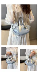 Detail showing a stylish light blue handbag with a silver bear charm and shoulder strap.