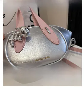 Detail of silver bucket bag with pink handles and a silver balloon dog charm.