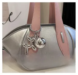 Close-up detail of silver fashion bucket bag with pink handles and balloon dog charm