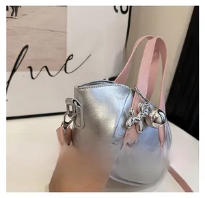 Side view showing details of fashionable silver bucket bag with pink handles and charms