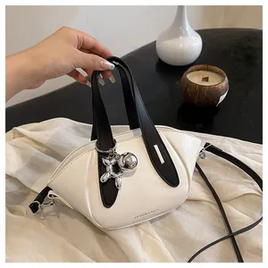 Close-up of a white bucket handbag with black handles and silver balloon dog charm.