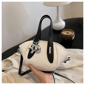 Detail view of a chic cream crossbody bucket bag with a silver balloon dog charm.