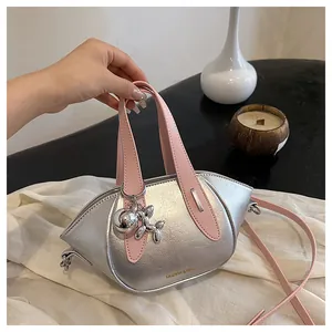 Close-up view of a chic silver metallic handbag featuring pink handles and a balloon dog charm