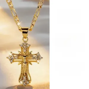 Close-up of golden crucifix pendant with shimmering zircons on a Figaro chain.