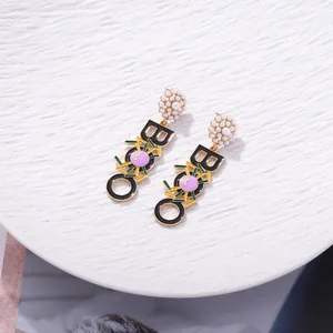 Spooky Halloween earrings featuring pearl studs, black BOO letters and purple spiders