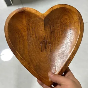 Detail view of a vintage heart-shaped wooden prayer bowl featuring carved crosses