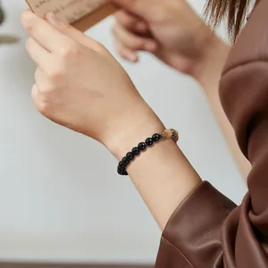 Detailed view of a natural stone beaded bracelet featuring black and brown beads on a wrist