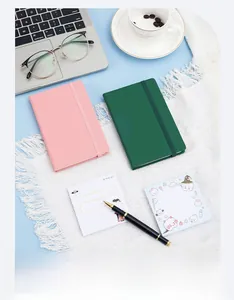 Carnets A6 compacts avec bande élastique en rose et vert sur un bureau stylisé