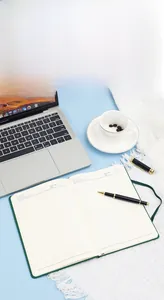 Gros plan d'un carnet A5 en cuir vert avec pages lignées sur un bureau de bureau