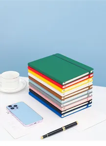 Multiple colorful A5 leather notebooks with elastic bands stacked on a bright office desk