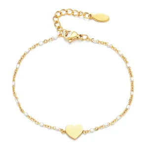 Elegant gold stainless steel heart pendant bracelet with white enamel beads on white background.