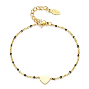Elegant gold-plated stainless steel heart bracelet with black enamel beads on white back.