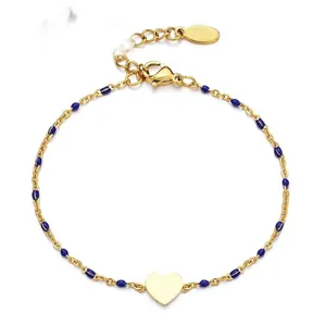 Detailed view of a gold-plated stainless steel bracelet with blue enamel beads and heart charm.