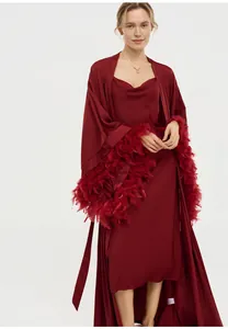 Détail d'un peignoir en satin bordeaux élégant avec une bordure luxueuse en plumes
