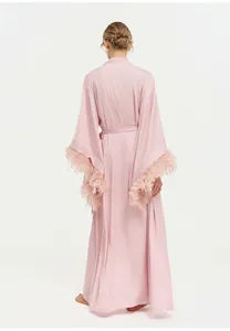Vue détaillée de dos d'un peignoir long rose de luxe avec poignets bordés de plumes.
