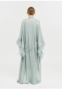 Vue arrière d'un peignoir long vert sauge élégant avec manches à plumes de luxe