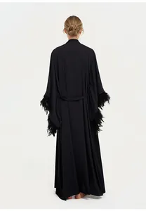 Vue arrière de l'élégante robe longue noire avec garniture en plumes luxueuses aux poignets