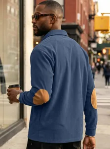 Detail view of blue ribbed corduroy long sleeve polo shirt with brown elbow patches for men.