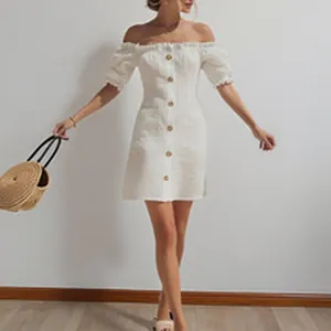 Close-up of white off-the-shoulder button-down mini dress on model with straw bag.