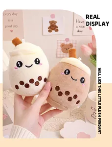 Detail view of two cute smiling bubble milk tea plush keychain charms held in hand
