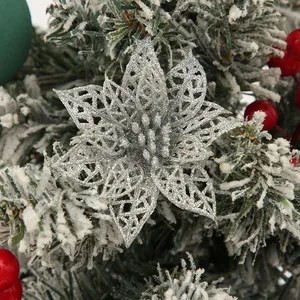 Detail shot of silver glitter poinsettia flower on snowy Christmas tree branch