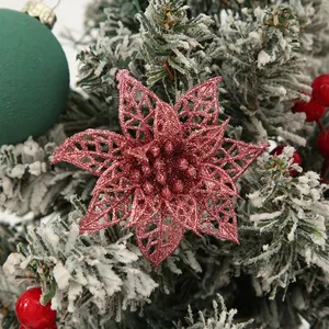 Glittery pink hollow Christmas poinsettia flower on a snowy pine tree branch