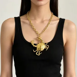 Detail shot of a punk style oversized gold crab pendant necklace worn on a model