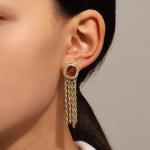 Close-up macro view of vintage gold tassel earrings with amber zircon on female ear